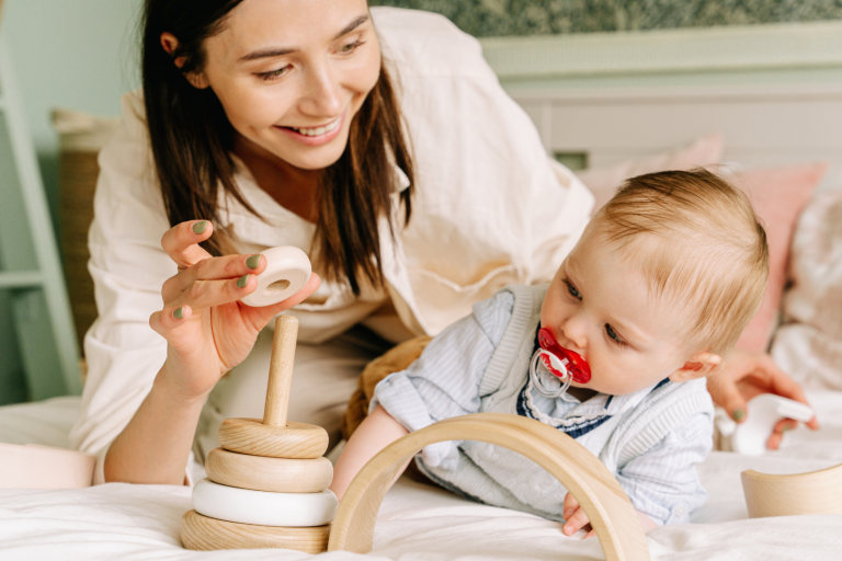 baby playing with toys and mum helping