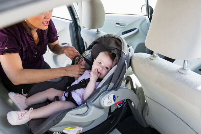 Lady assisting child into car seat