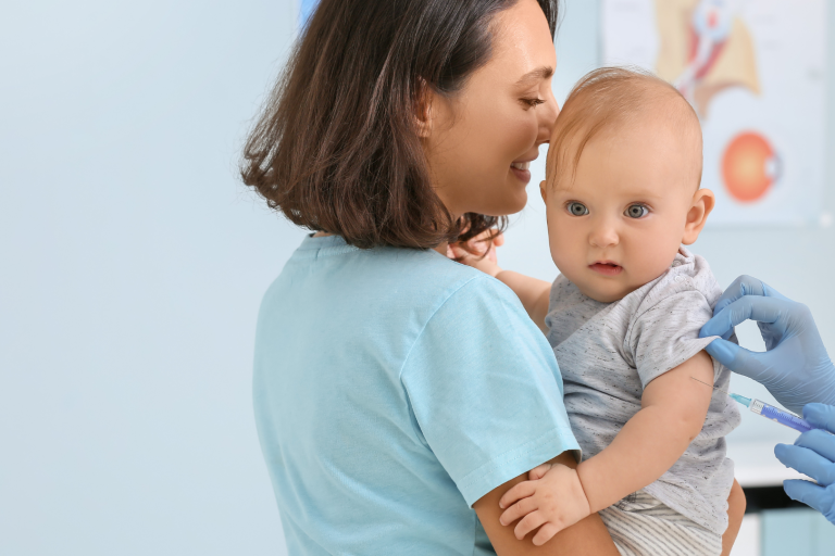 Lady holding a baby being vaccinated