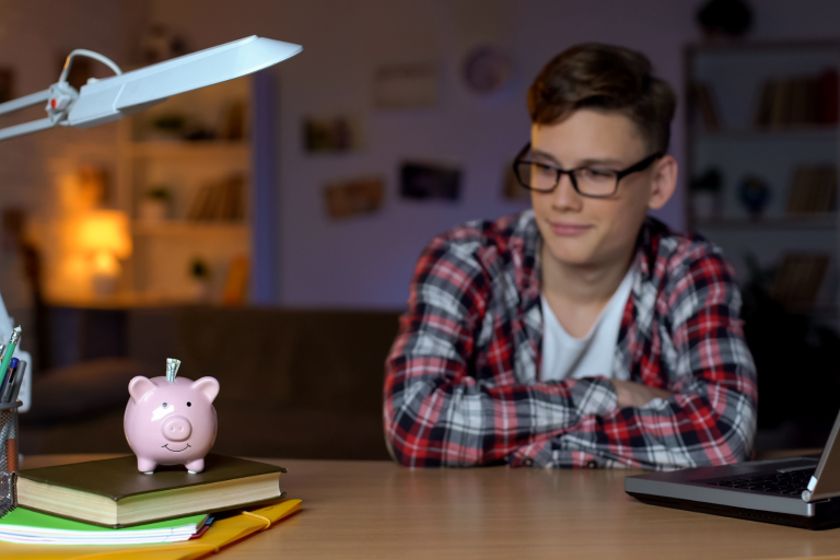 Teenager looking at a piggy bank