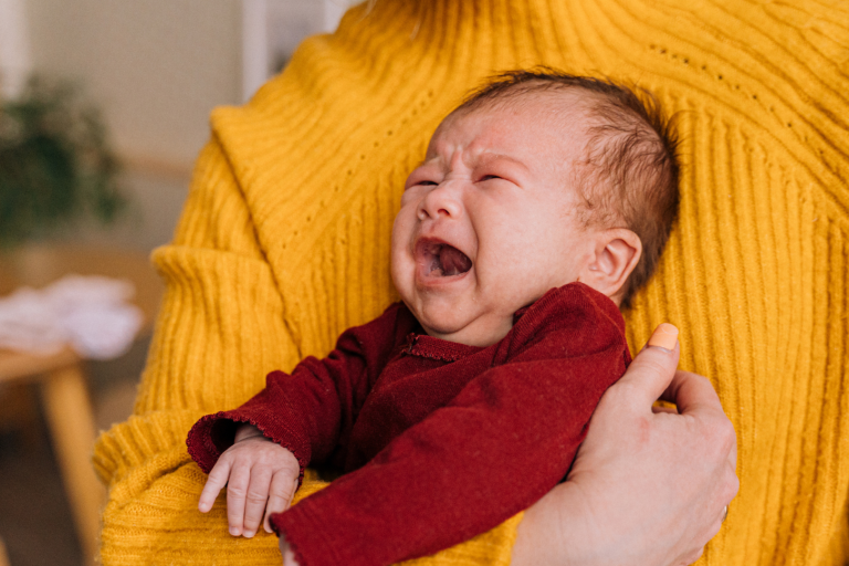 Baby crying in arms of parent