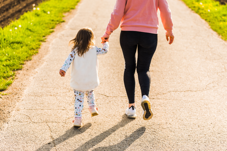 mum and toddler walking on country path from behind