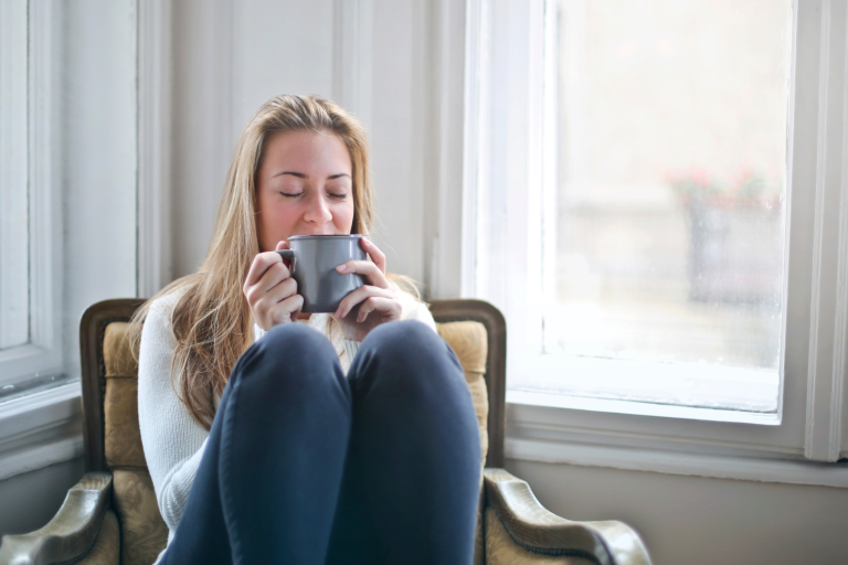 Lady with a cup of tea sitting with her knees up on chair