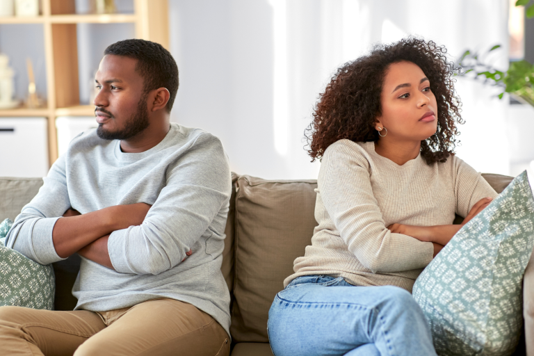 Couple sitting on sofa with back to each other