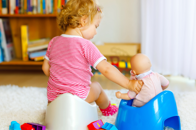 Young girl sitting on a potty with holding a doll sitting on a potty