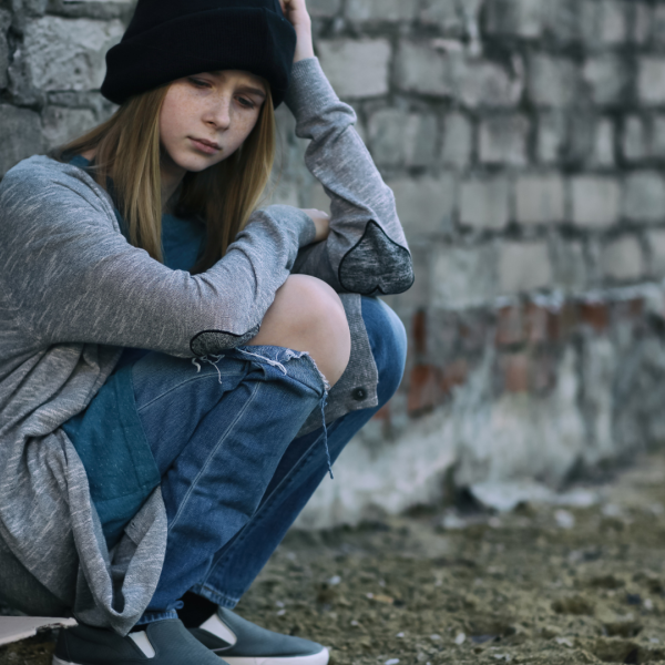 Teenage girl knelt down with back up against brick wall